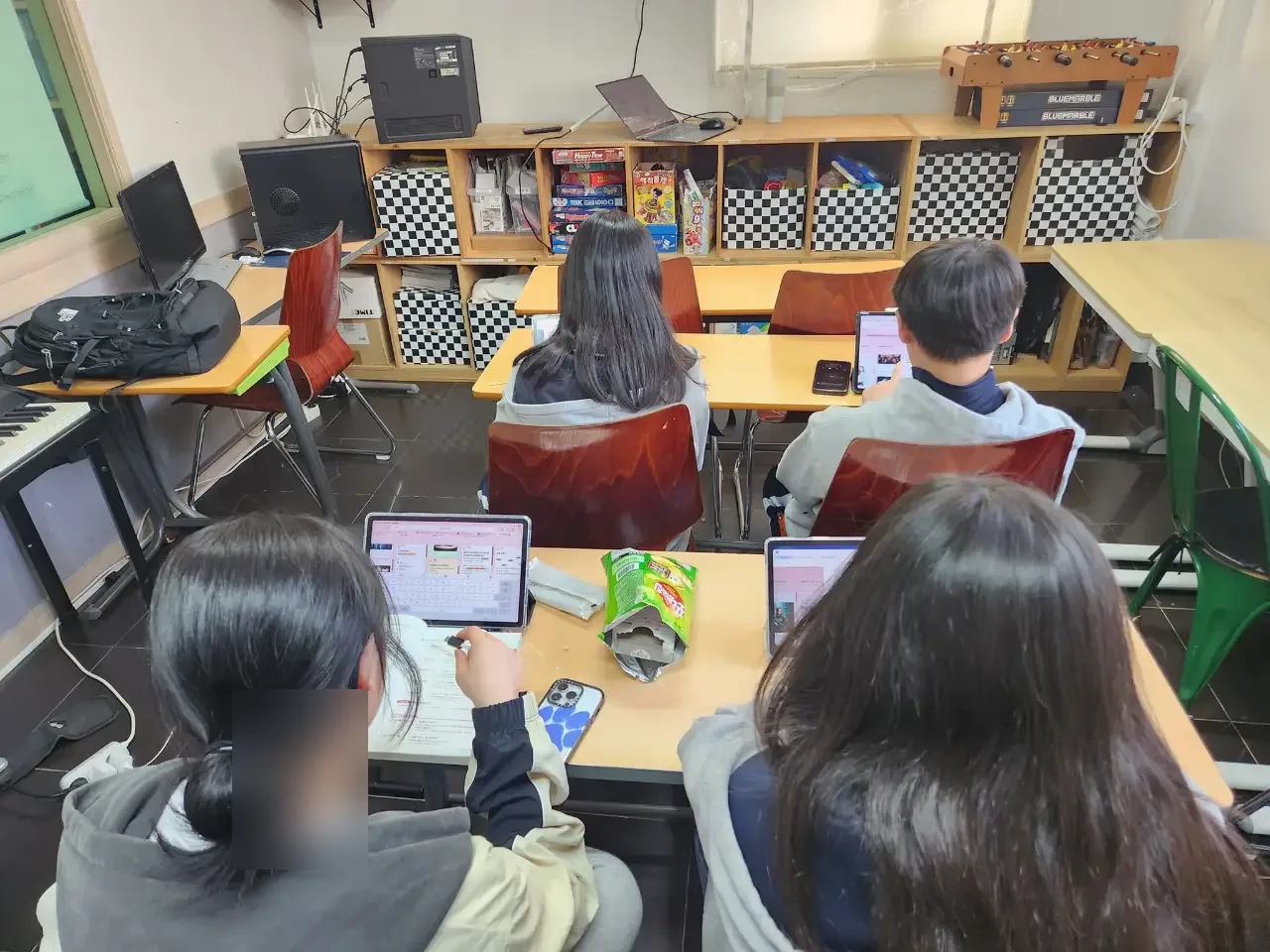 지역아동센터 교실에서 태블릿을 보는 학생들의 뒷모습