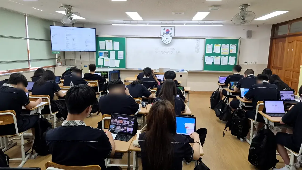 교복을 입은 중학생들이 앉아 있는 교실 뒷모습 (얼굴 흐림 처리)