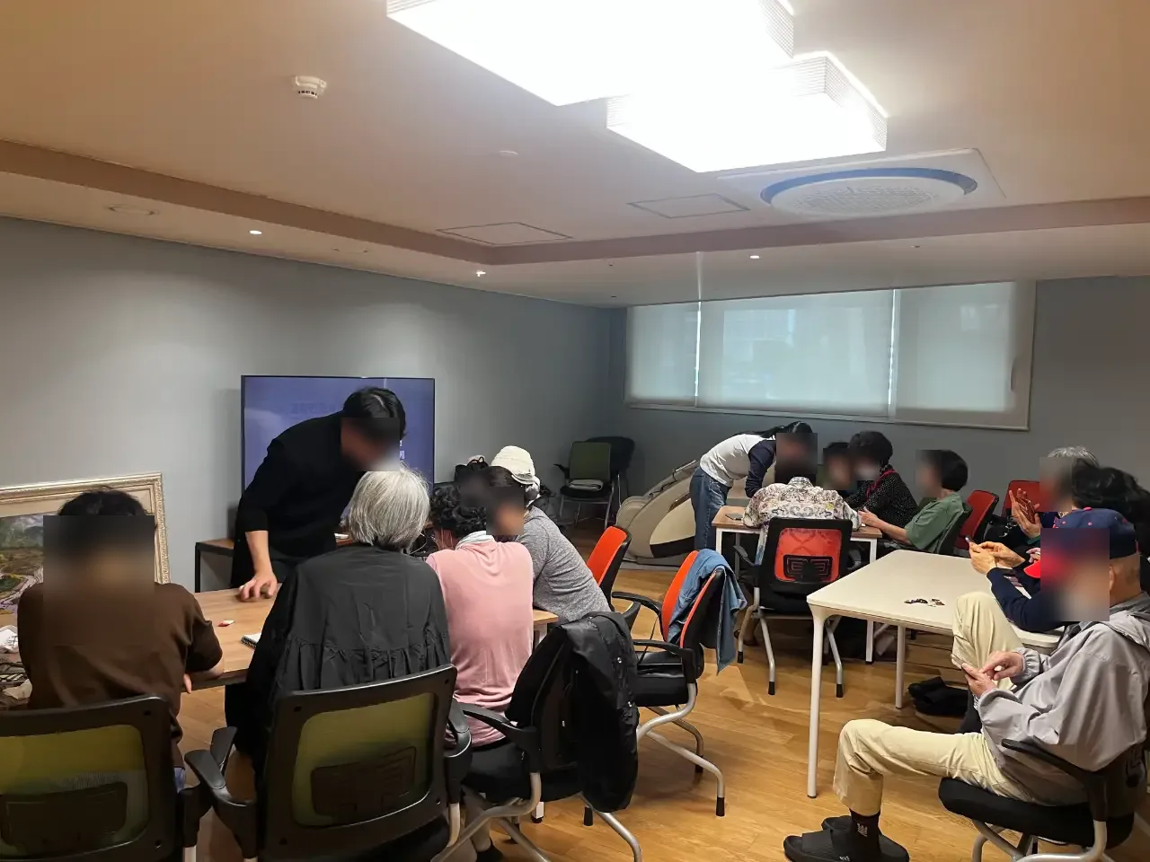 경로당에서 봉사자와 함께 기기를 다루는 어르신들 (얼굴 흐림 처리)