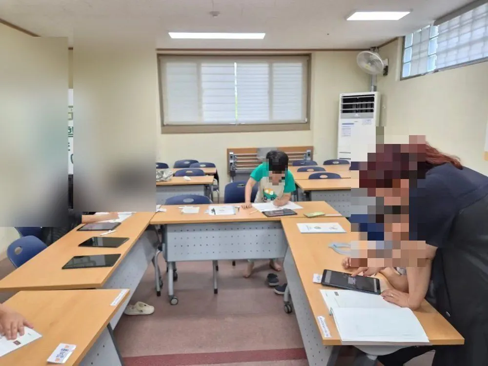 아이 옆에서 화면을 함께 보며 돕는 선생님