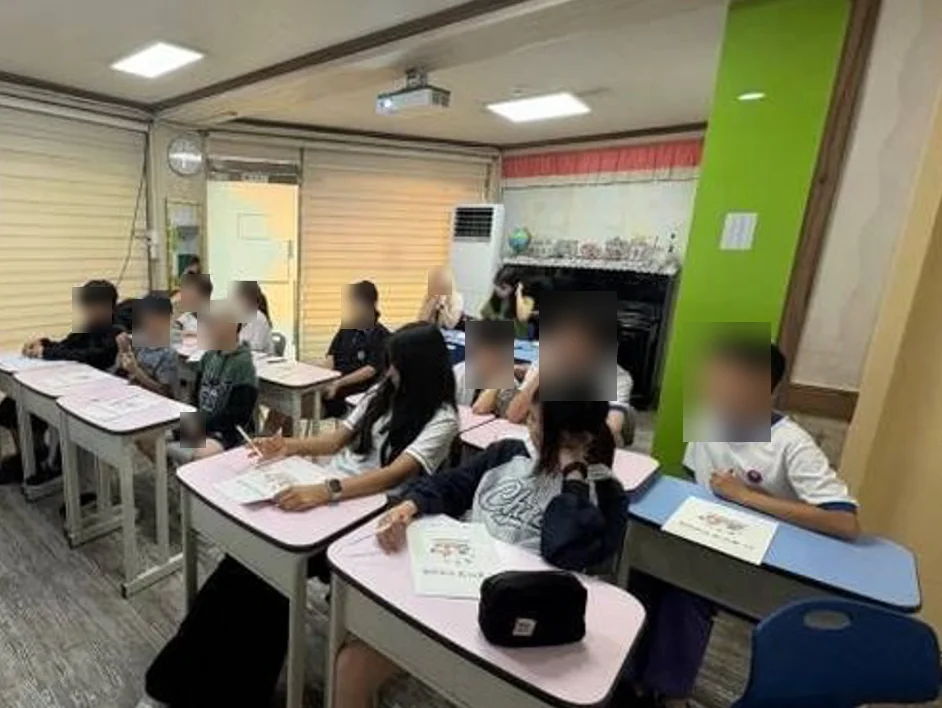 지역아동센터에서 워크북을 펴고 토론 수업에 참여하는 학생들 (얼굴 흐림 처리)